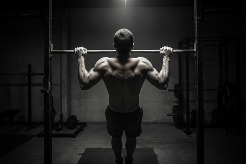 person doing pull ups in a dark gym. hes grinding